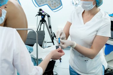 Anestezi uzmanları beyaz cerrahi giysiler, maskeler ve steril eldivenlerle bir ampulden şırınga dolduruyorlar. Epidural anestezi ve ameliyat için hazırlık.