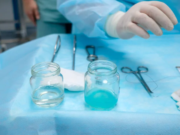 Sterilní chirurgické nástroje a skleněné nádoby s roztoky na stole během chirurgické operace. — Stock fotografie