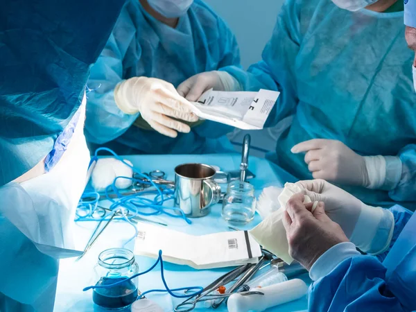Un grupo de cirujanos que realizan una cirugía mínimamente invasiva en el ano de los pacientes utilizando instrumentos quirúrgicos . — Foto de Stock