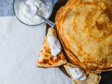 Düz yatıyordu. Kahverengi bir tabakta taze pişmiş pembe krep yığını. Yakınlarda beyaz ekşi kremalı ve metal kaşıklı cam şeffaf bir fincan var. Köyden lezzetli bir kahvaltı..