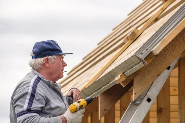 Senior Construction Man Med Hjälp Skruvmejsel Fäster Ett Tak Blad — Stockfoto