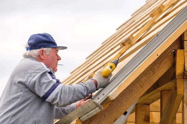 Senior Gråhårig Byggherre Med Hjälp Skruvmejsel Fäster Takplåt Trä Takbjälkar — Stockfoto