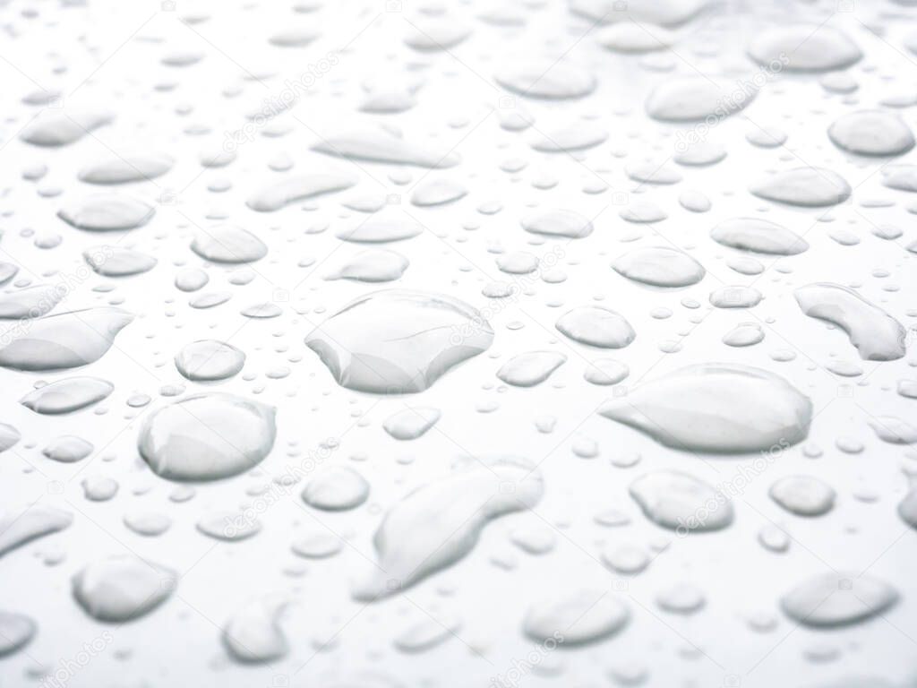 Transparent drops of water on a white glossy surface. Abstract background with strong blur zone of blur.