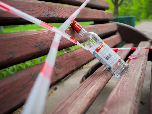 莫斯科 俄罗斯 2020年5月14日 公园的长椅被红白相间的信号带包裹着 长椅上有一瓶空的伏特加 Coronavirus检疫期间的限制 — 图库照片