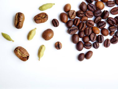 Flat lay. Coffee beans and cardamom grains are scattered on a white glossy surface. Shallow depth of field and highly blurred background. Copy space.  clipart