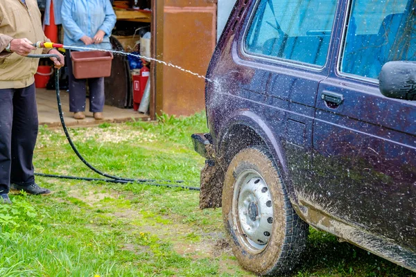 Siwy Starzec Myje Samochód Zewnątrz Wężem Ogrodowym Potężny Strumień Wody — Zdjęcie stockowe