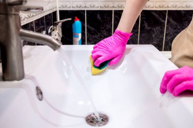 Pembe eldivenli bir el banyodaki lavaboyu köpüklü deterjanlı bir süngerle yıkıyor. Temizlik şirketi evi temizliyor. Bunak düğümü virüslerden ve bakterilerden dezenfekte olmuş..