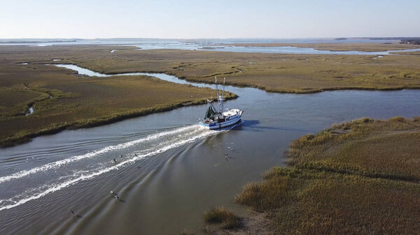 Aerial view of commercial fishing boat coming into port.