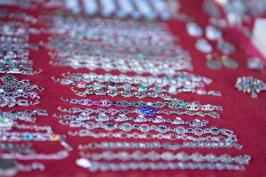 Kadınlar için elinde çok renkli taşlar olan metal bilezikler.