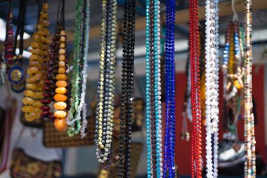 Farklı taşlardan boncuklar bir stantta asılı.