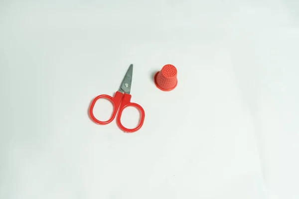 Red thimble and scissors lie on a white background — Stock Photo, Image