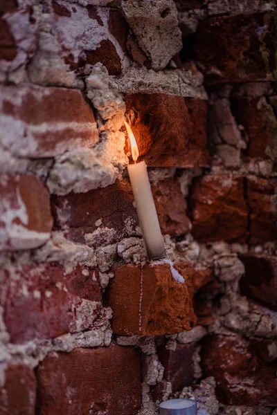 White wax candle burns on a brick background — 스톡 사진