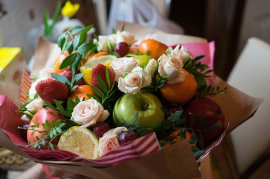 fruit and berry bouquet with roses in a package