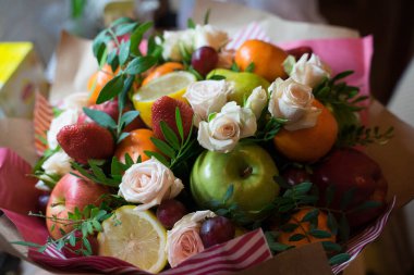 fruit and berry bouquet with roses in a package