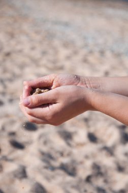 Kum ellerden dökülür. Deniz kıyısındaki kumsalda