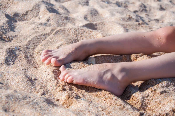 Children's feet in the sand on the beach. White sand