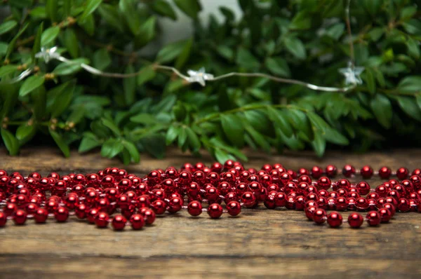 Újévi Piros Dekorációk Egy Asztal Hátterében Zöld Ágak — Stock Fotó