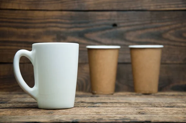 白いカップと紙コップは木製のテーブルの上に立つ 朝のお茶とコーヒー — ストック写真
