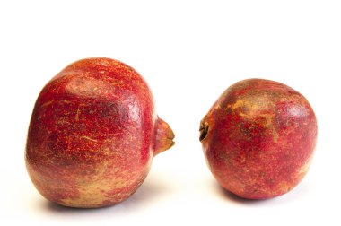 Olgun kırmızı nar beyaz bir arkaplanda bir masanın üzerinde yatıyor..