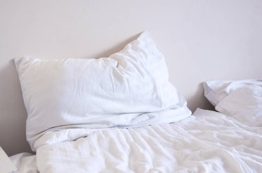 Beyaz yatak. Yastık örtüsü. Odada yatak.