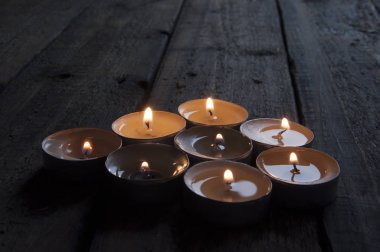 Lighted small candles laid out in a row on a wooden table. Texture. Symbol. Holidays love day