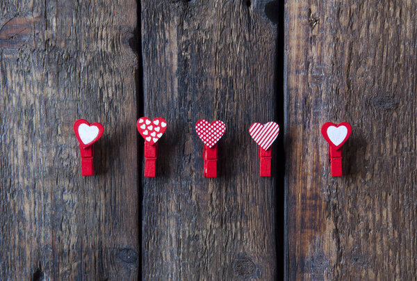 Little red clothespins hearts on a wooden background. Love