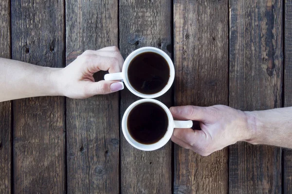 女性と男の手が木の背景に保持されているお茶やコーヒーと2つの白いカップ — ストック写真