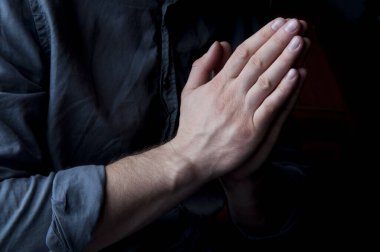 Dua ederken ellerinizi birleştirin. Tanrı 'ya sorar. Gömlekli bir adamın elleri. Bir adam dua ediyor.