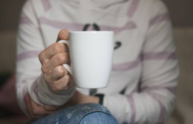 Elde bir fincan. Beyaz bardak bir kadının elinde..