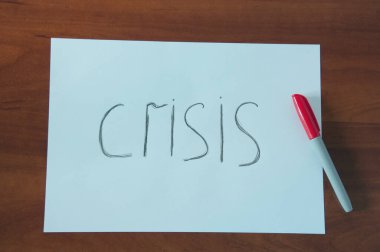 Kriz kelimesi beyaz sayfada. Masada kalem işareti var.