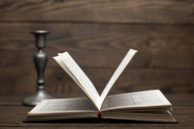 Ahşap bir masada İncil 'in açık kitabı. Antika şamdan.