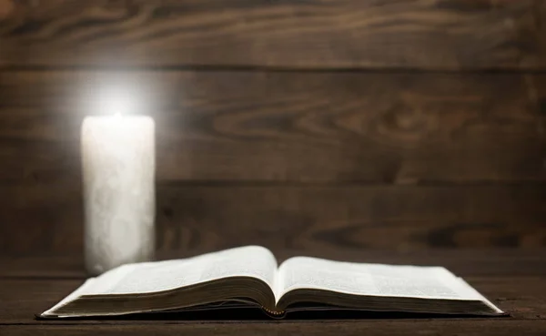 圣经翻开的书放在木制桌子上 点燃的蜡烛 — 图库照片