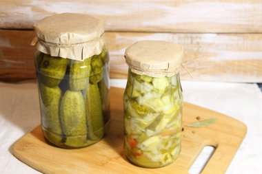 Cam kavanozda baharatlı salatalık turşusu ve beyaz arka planda ahşap bord 'da salata.