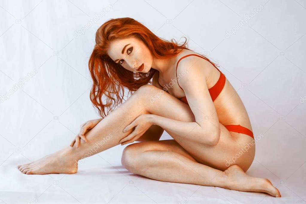 attractive young redhead woman in red underwear sitting on floor