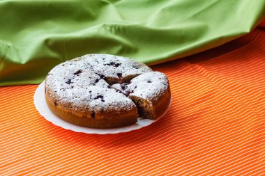 Yeşil ve turuncu renkli kumaşlar üzerine beyaz bir plaka üzerinde ev yapımı kek