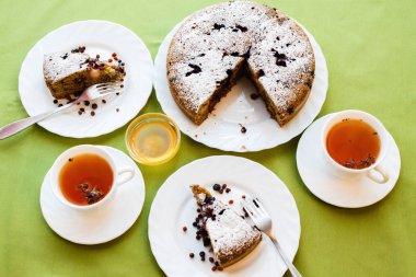 Çay içme. Yeşil ve turuncu renkli kumaşlar üzerine beyaz bir plaka üzerinde ev yapımı kek