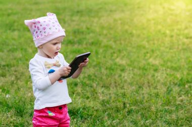 Tablet dijital bilgisayar açık havada tutan şirin küçük kız