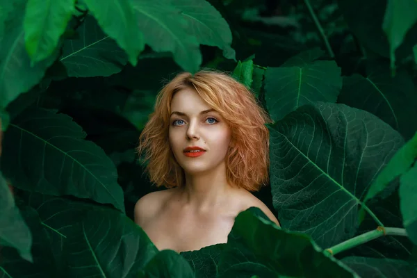 Retrato bela jovem mulher da moda com cabelo loiro cercado por folhas verdes — Fotografia de Stock