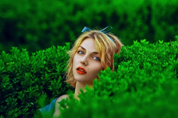 肖像美丽金发年轻时尚女人包围绿色的树叶 — 图库照片