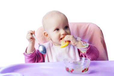 Küçük bebek kız masada beyaz bir arka plan üzerinde izole limon yiyor