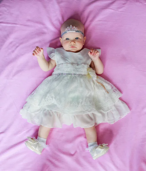 Retrato de uma linda menina princesa uma coroa na cabeça deitado fundo rosa — Fotografia de Stock