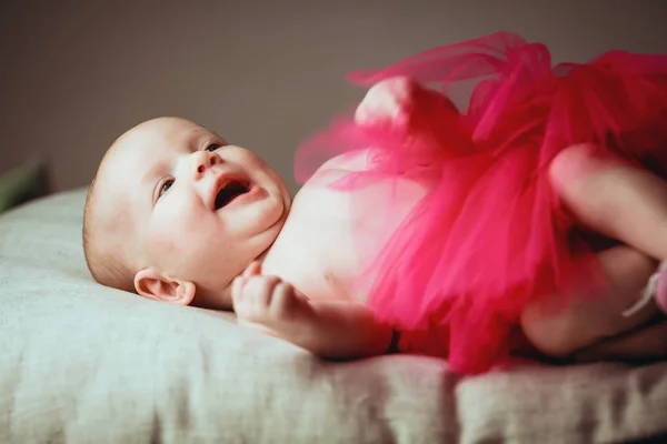 Retrato de un ríe muy ruidosamente lindo bebé de 1-2 meses de edad en la almohada en falda de bailarina —  Fotos de Stock