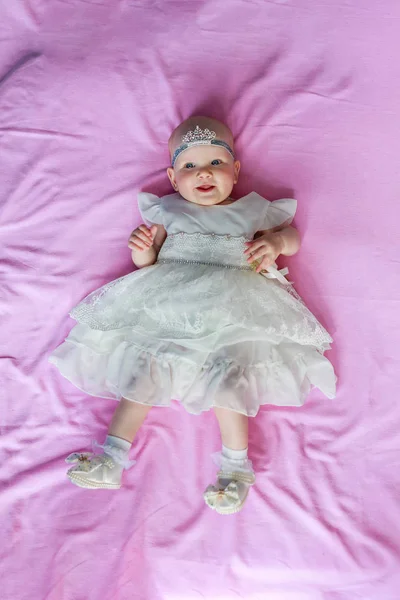 Retrato de una linda niña con una corona en la cabeza de fondo rosa — Foto de Stock