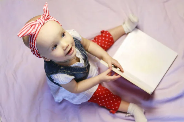 Retrato de uma adorável menina sentada e olhando para um livro — Fotografia de Stock