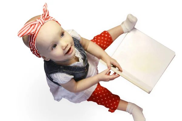 Porträt eines entzückenden Mädchens, das aufsitzt und ein Buch betrachtet, isoliert auf weiß — Stockfoto