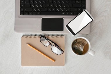 Kavram işyeri üstten görünüm. Dizüstü bilgisayar, boş ekran, defter, telefonu ve fincan çay ile Designer Danışma