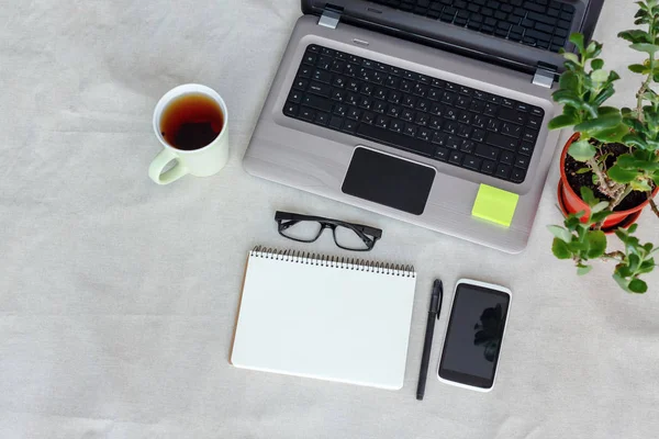 Komfort pracy widok z góry. Projektant biurko z pusty ekran, notebook, laptop, telefon i filiżanki herbaty — Zdjęcie stockowe