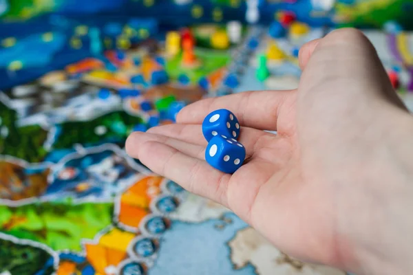 Hand hold the dice on the background of colorful blurred Board games — Stock Photo, Image
