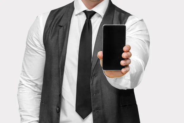 Бизнесмен показывает свой смартфон изолирован на сером фоне, смартфон в руке — стоковое фото