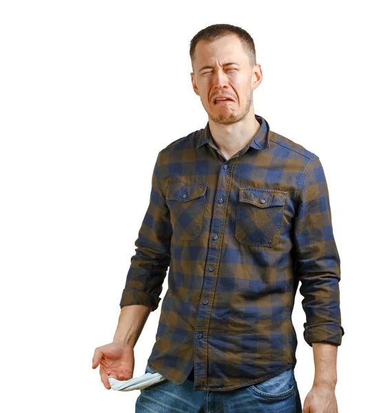 No money concept. Young man in a checkered shirt showing empty pockets, sad unhappy face expression. Isolated on white background